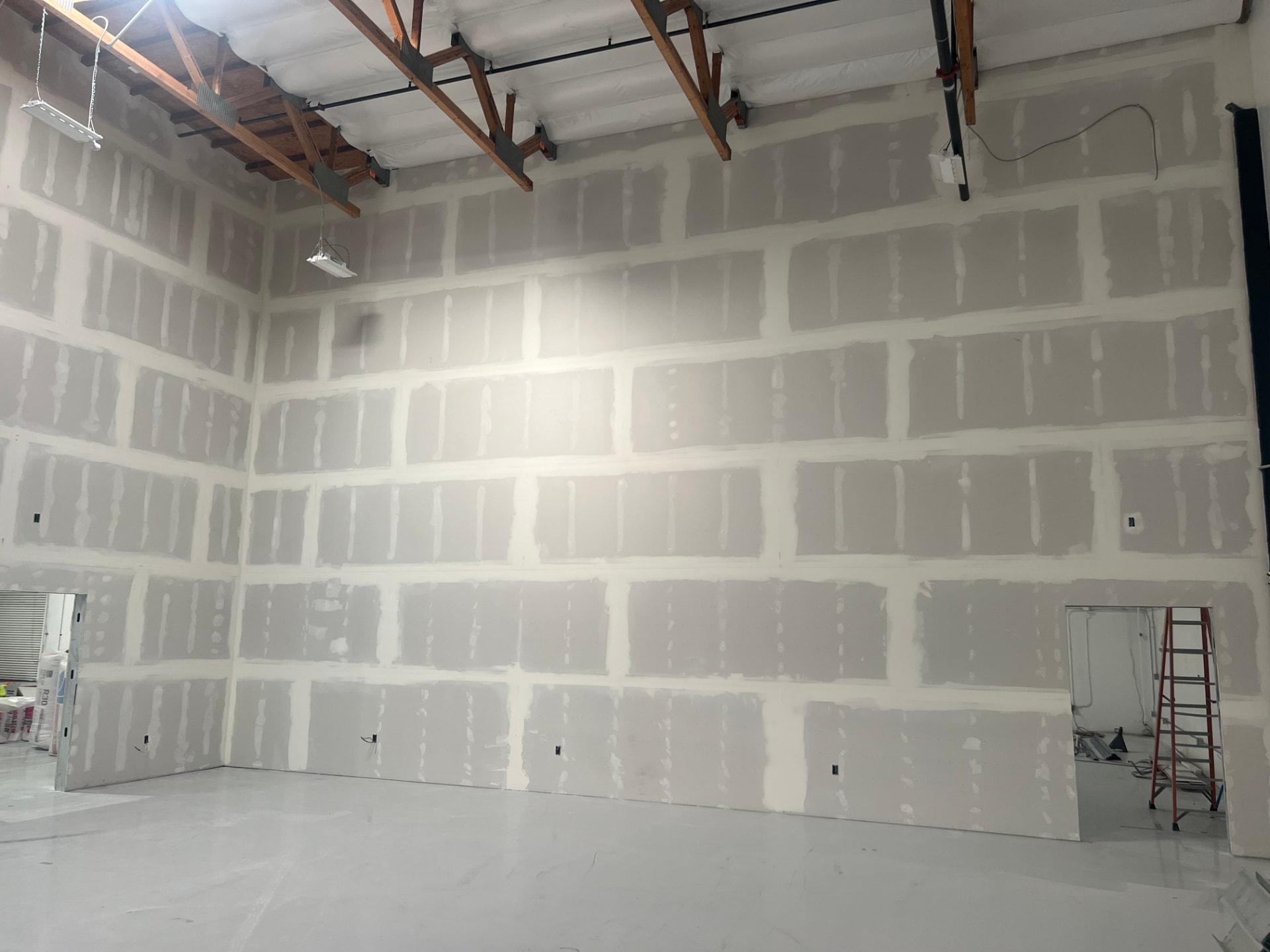 Taped and floated drywall demising wall running full height to the roof deck in a warehouse shell