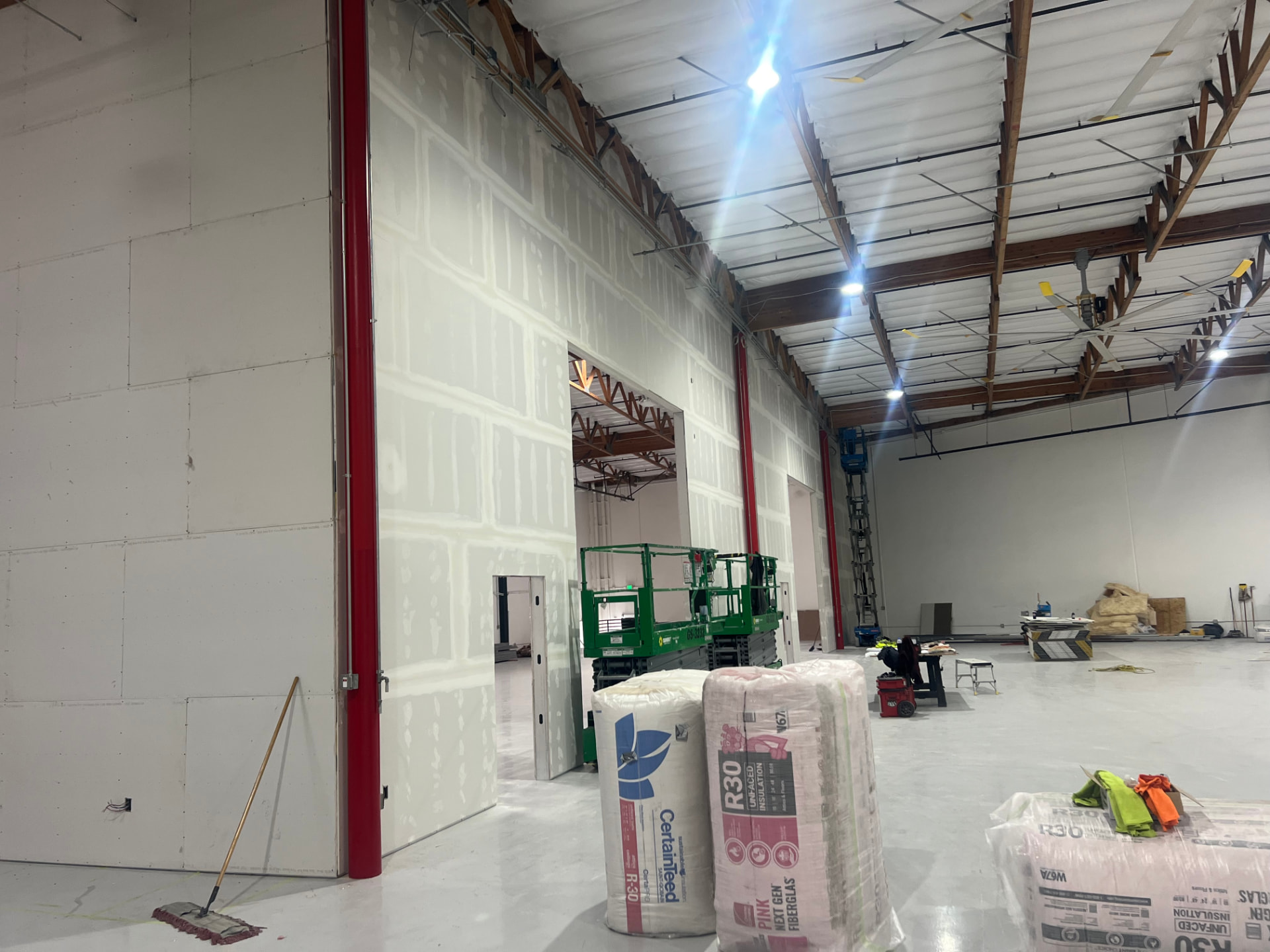 Tenant improvement in progress with scissor lifts, insulation rolls and painted steel columns